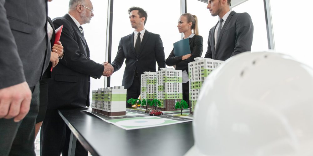 Business meeting of architects and investors looking at model of residential quarter houses
